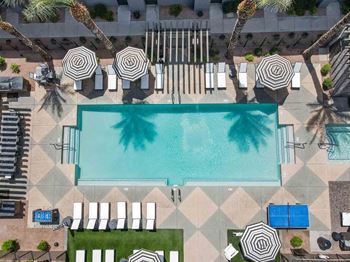 An aerial view of a pool surrounded by palm trees and lounge chairs.